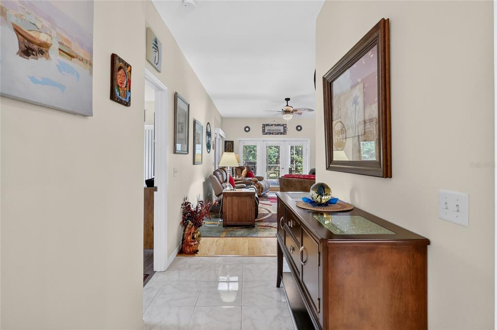 A tiled hallway leads to a living room with hardwood floors and glass patio doors — 4188 ABERDEEN LANE, LAKE WALES, FL