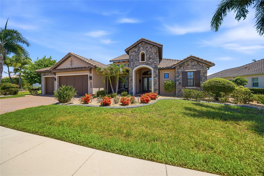 A single-story house with a stone facade, a tiled roof, and a paved driveway — 13220 CAMPANILE COURT, VENICE, FL