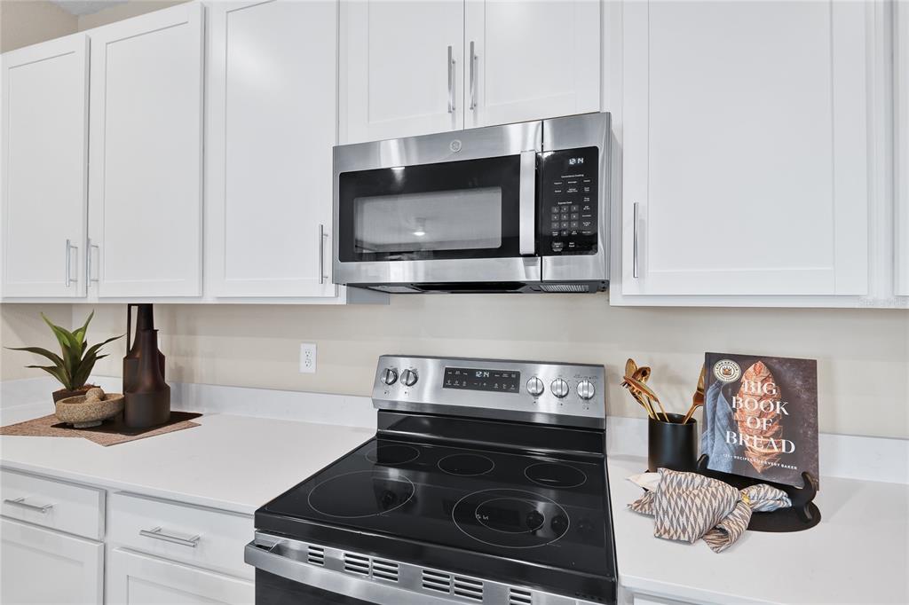 A kitchen features white cabinets, stainless steel appliances, and a black electric range — 1269 DAISY HILL AVENUE, DUNDEE, FL