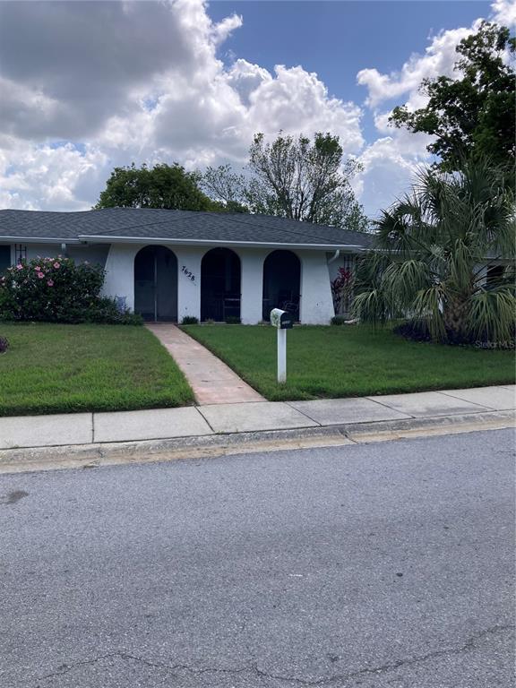 A single-story house features a white facade with three arched entryways and a front lawn — 7628 VALLEY COURT, NEW PORT RICHEY, FL