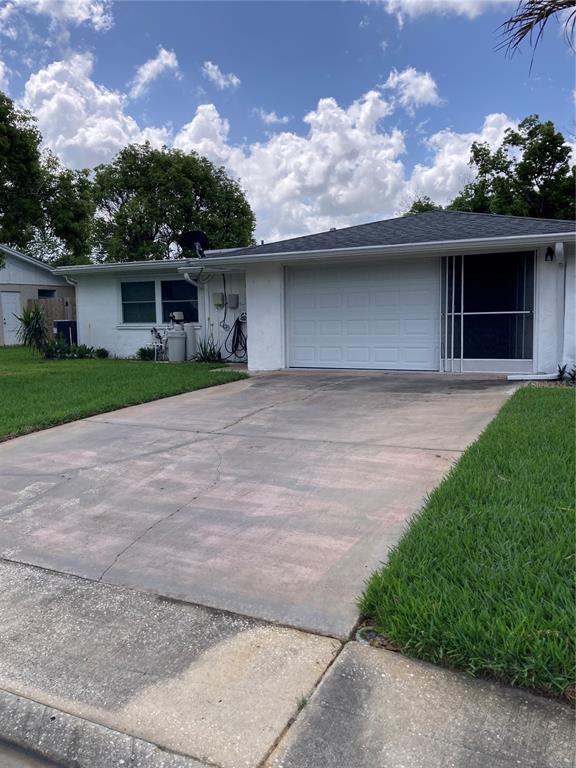 A white single-story house with a garage, a concrete driveway, and a green lawn — 7628 VALLEY COURT, NEW PORT RICHEY, FL