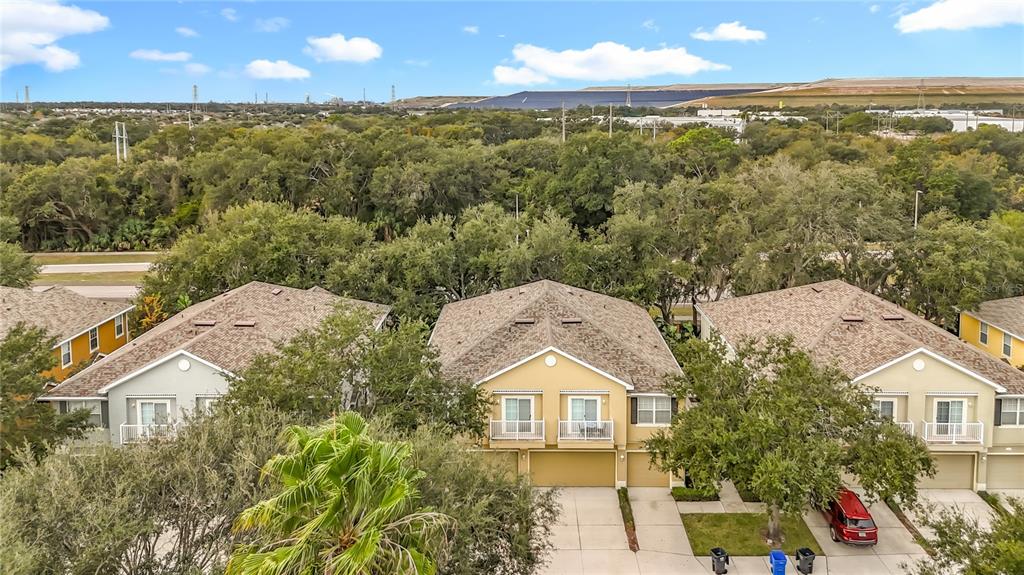 An aerial view shows three multi-story townhomes with beige siding and shingled roofs — 6811 BREEZY PALM DRIVE, RIVERVIEW, FL