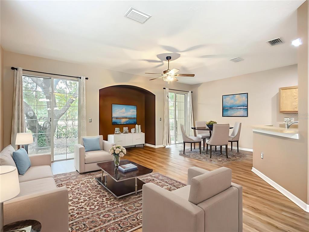 A living and dining area features wood-look flooring, a dark accent wall, and sliding glass doors — 6811 BREEZY PALM DRIVE, RIVERVIEW, FL