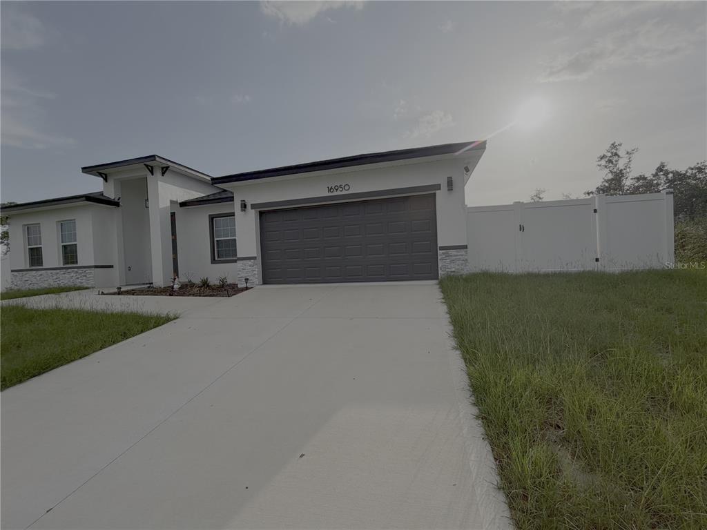 A modern single-story house with a white exterior, stone accents, and a two-car garage — 16950 SW 42ND AVENUE ROAD, OCALA, FL