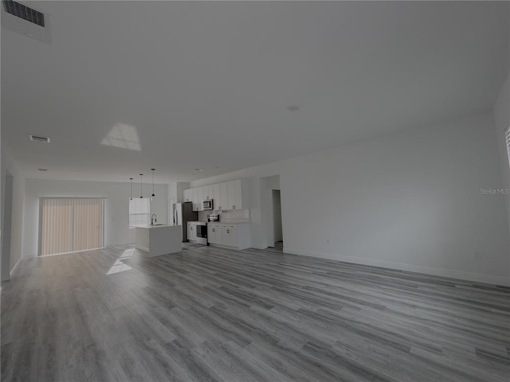 An open-concept kitchen and living area feature white cabinets, a kitchen island, and wood-look flooring — 16950 SW 42ND AVENUE ROAD, OCALA, FL