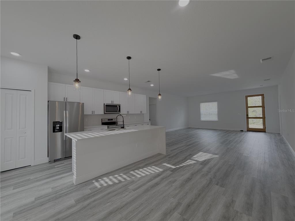 A modern kitchen with white cabinets and a center island opens into a living area — 16950 SW 42ND AVENUE ROAD, OCALA, FL