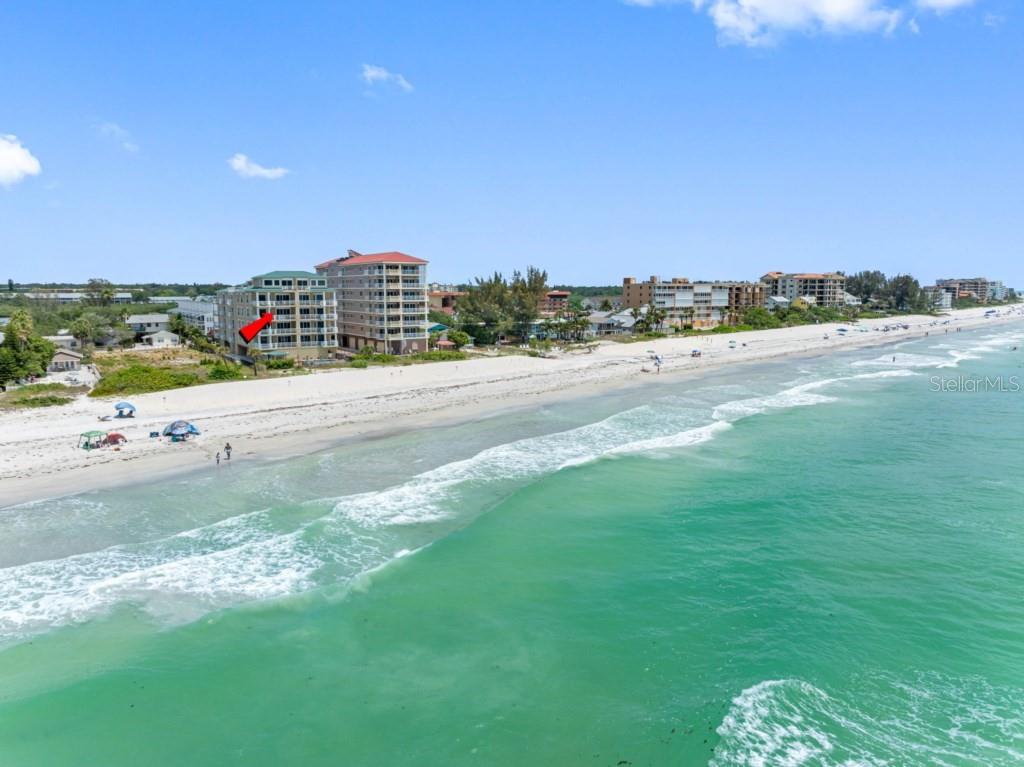 An aerial view of a multi-story beachfront condominium building along a sandy coastline — 19734 GULF BOULEVARD UNIT 402, INDIAN SHORES, FL