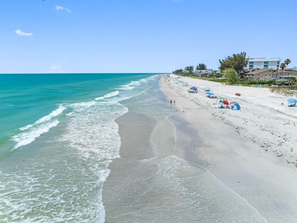 An aerial view of a sandy beach with turquoise water and several beach umbrellas — 19734 GULF BOULEVARD UNIT 402, INDIAN SHORES, FL