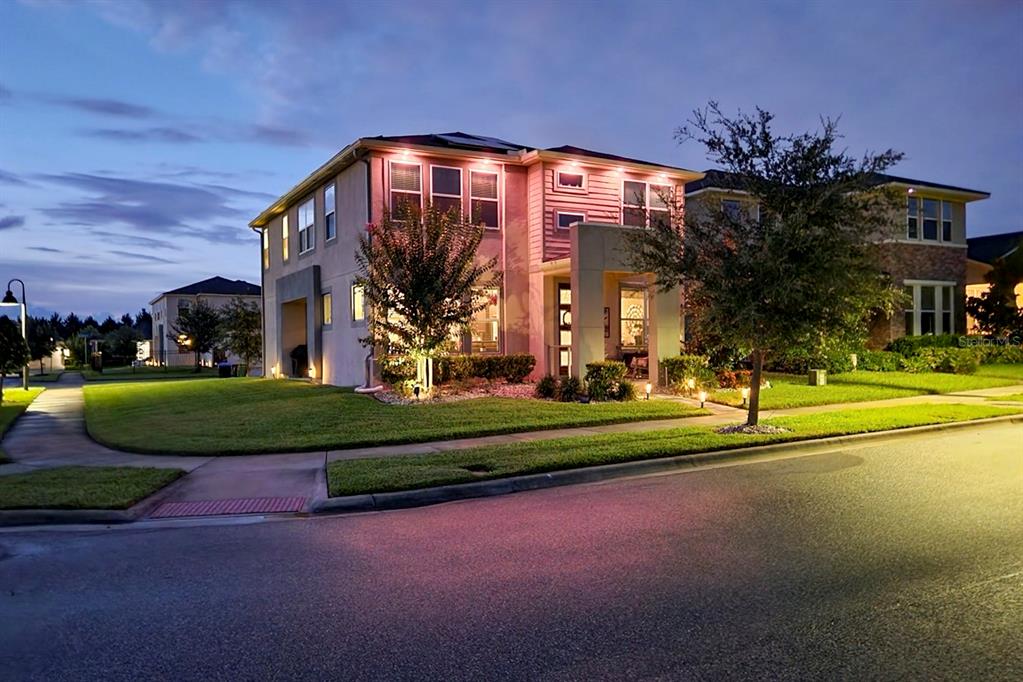 A two-story suburban house with exterior lighting at dusk, featuring a lawn and sidewalk — 16185 TALIESIN STREET, WINTER GARDEN, FL