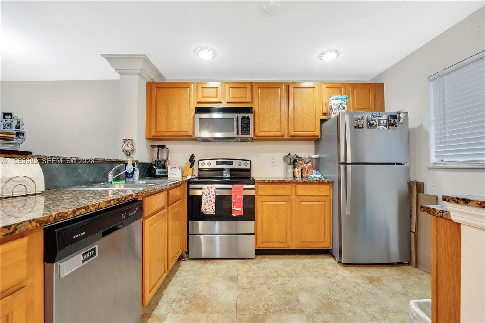 A kitchen features light wood cabinets, granite countertops, and stainless steel appliances — 3777 NW 78th Ave # 15G, Davie FL 33024, DAVIE, FL