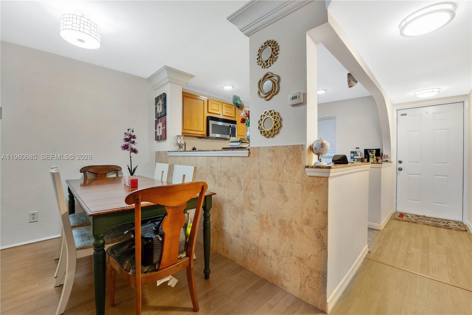 A dining area sits adjacent to a kitchen with a tiled half-wall and entryway — 3777 NW 78th Ave # 15G, Davie FL 33024, DAVIE, FL