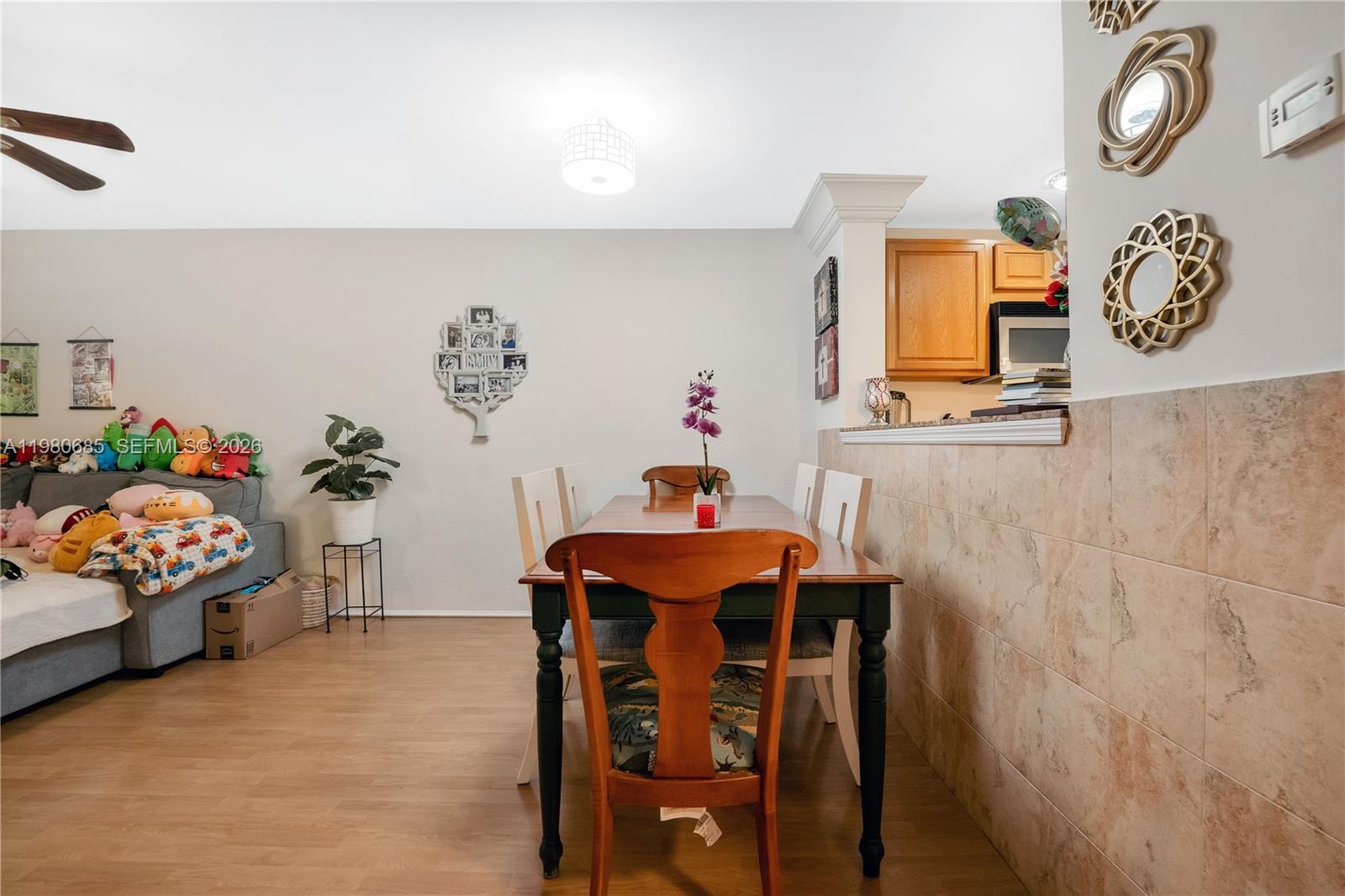 A dining area features a wooden table, chairs, and a tiled wall adjacent to a kitchen — 3777 NW 78th Ave # 15G, Davie FL 33024, DAVIE, FL
