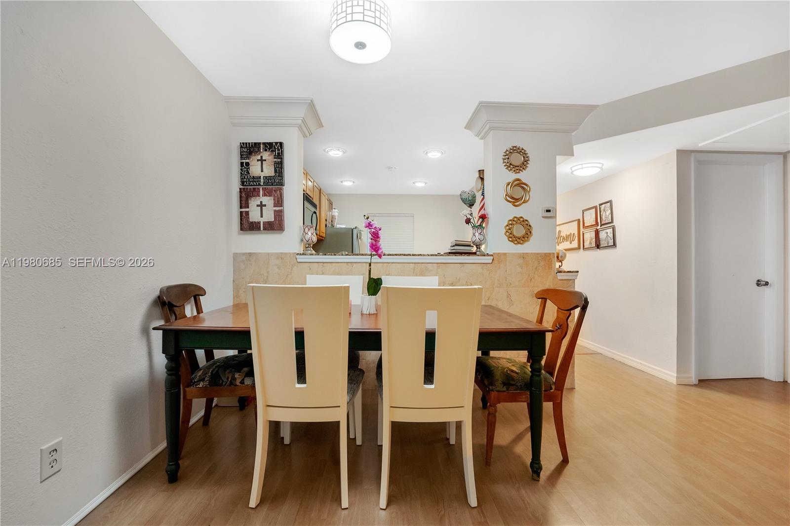 A dining area features a wooden table with mixed chairs, light flooring, and a kitchen pass-through — 3777 NW 78th Ave # 15G, Davie FL 33024, DAVIE, FL
