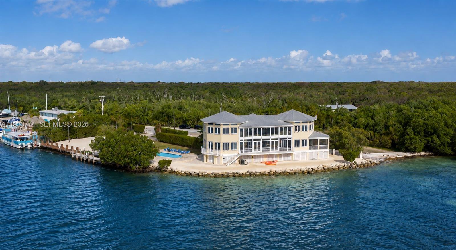 An aerial view shows a yellow waterfront house with a pool and boat dock — 57 Garden Cove Dr, Key Largo FL 33037, KEY LARGO, FL