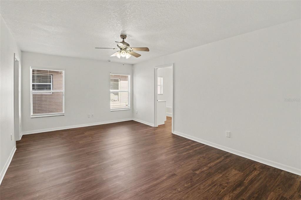 An empty living room features white walls, wood-look flooring, and a sliding glass door — 1544 ALGONKIN LOOP, ORLANDO, FL