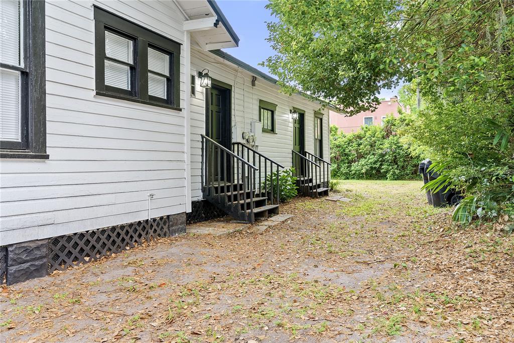The exterior of a white house features two sets of stairs leading to black doors — 412 E HARWOOD STREET UNIT 3, ORLANDO, FL