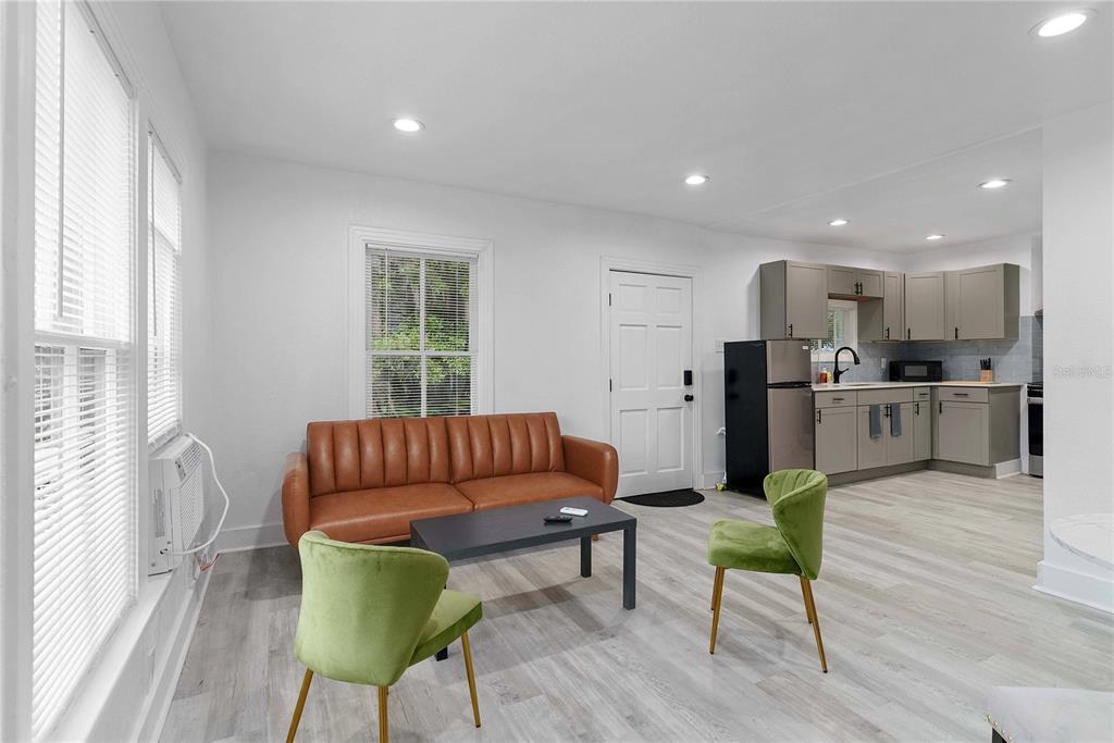 A living room with a brown sofa and two green chairs opens into a kitchen — 412 E HARWOOD STREET UNIT 3, ORLANDO, FL