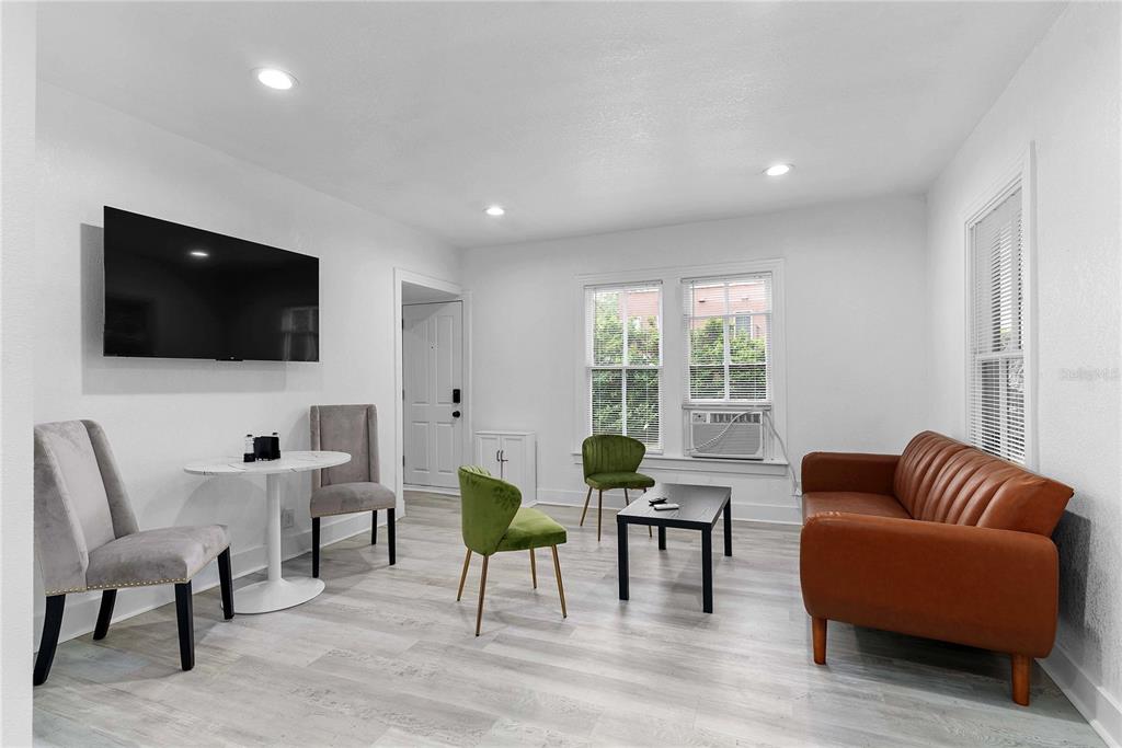 A living room features light wood-look flooring, a brown leather sofa, and a dining area — 412 E HARWOOD STREET UNIT 3, ORLANDO, FL