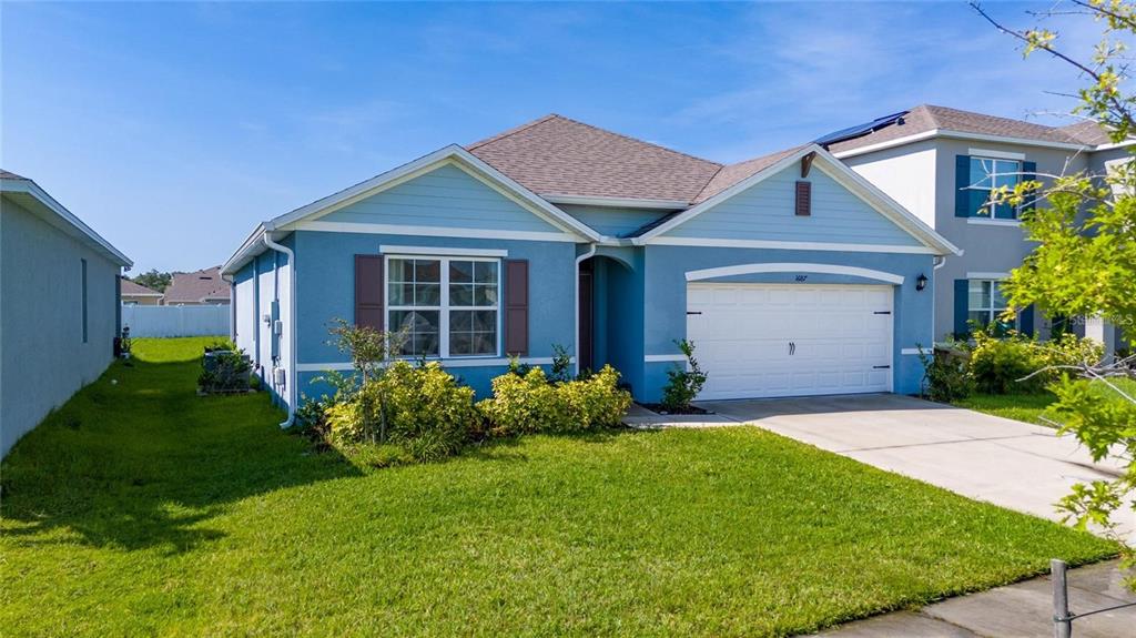 A blue, single-story suburban house with a two-car garage and a front lawn — 1687 PARK SIDE AVENUE, KISSIMMEE, FL