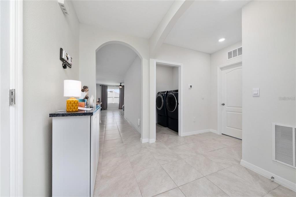 A bright hallway features light tile flooring, an arched entryway, and a laundry room — 1687 PARK SIDE AVENUE, KISSIMMEE, FL