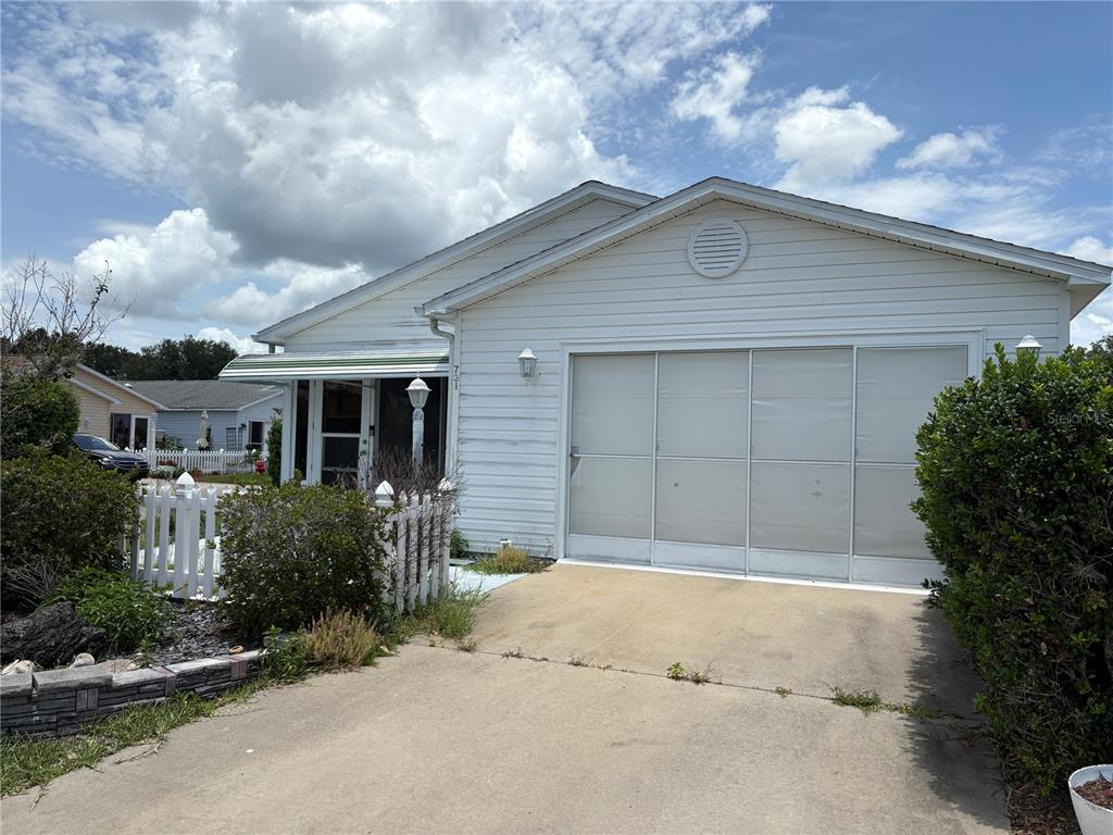 A white, single-story house features a sliding screen door over the garage and a picket fence — 731 DUMAS STREET, THE VILLAGES, FL