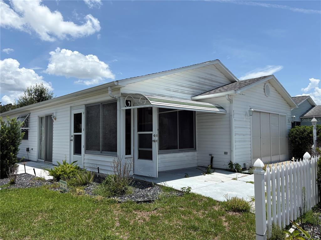 A white single-story house with a screened-in porch and a white picket fence — 731 DUMAS STREET, THE VILLAGES, FL