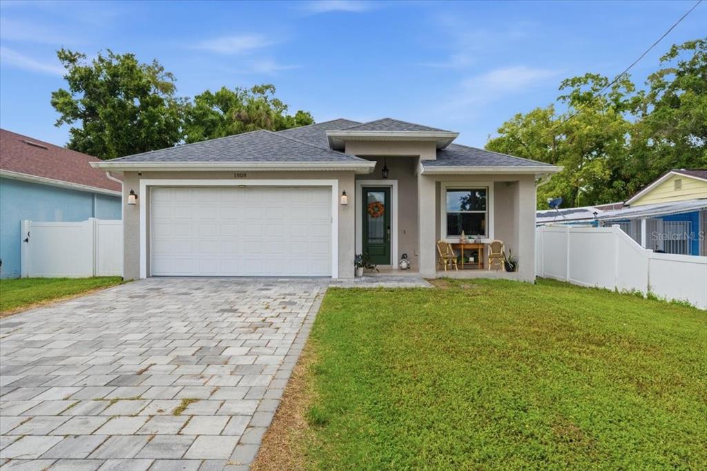 A single-story house with a paved driveway, a garage, and a white vinyl fence — 1808 W CLUSTER AVENUE, TAMPA, FL