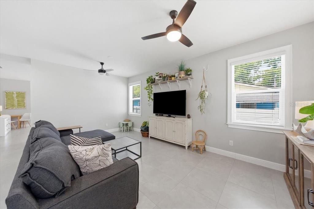 A living room features a grey sectional sofa, a television on a console, and tile flooring — 1808 W CLUSTER AVENUE, TAMPA, FL