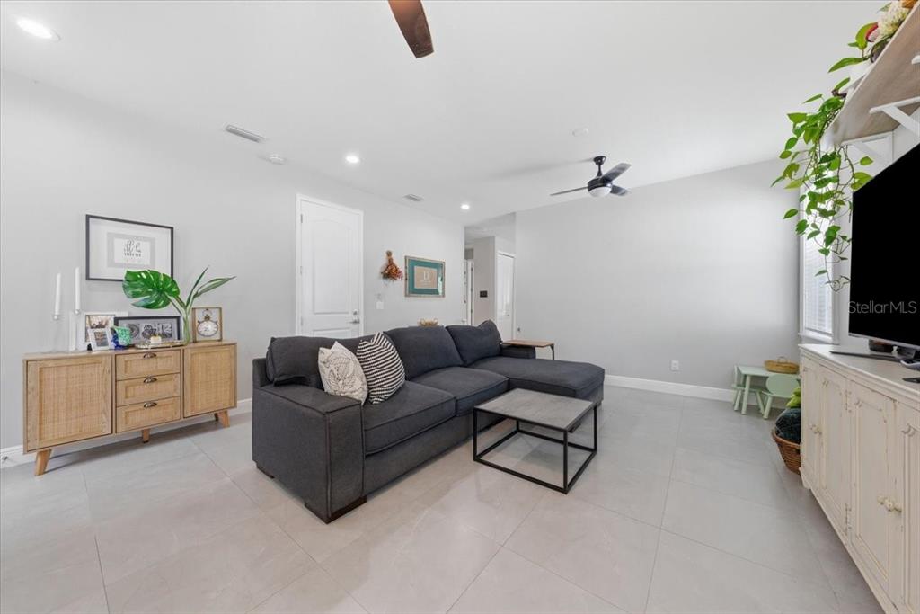 A living room features a gray sectional sofa, a wooden sideboard, and light tile flooring — 1808 W CLUSTER AVENUE, TAMPA, FL