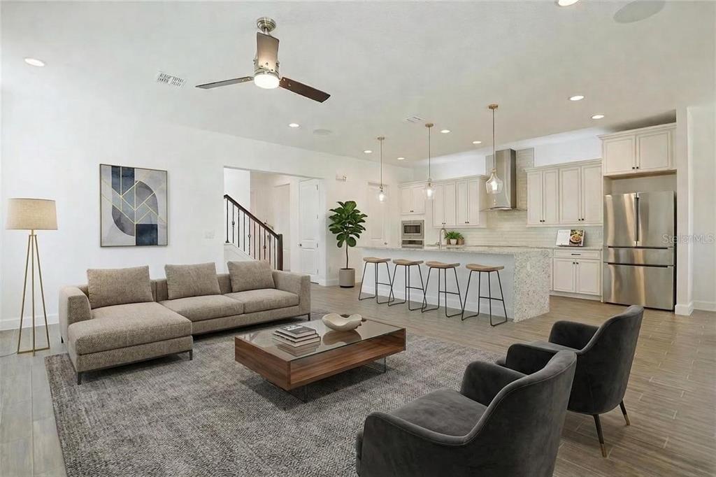 An open-concept living room and kitchen featuring a sectional sofa, island seating, and neutral decor — 7038 ARNOLDSON STREET, ORLANDO, FL