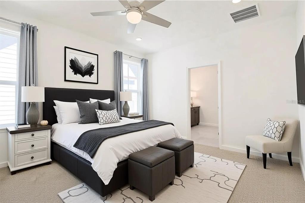 A bedroom features a black upholstered bed, two gray ottomans, and a white accent chair — 7038 ARNOLDSON STREET, ORLANDO, FL