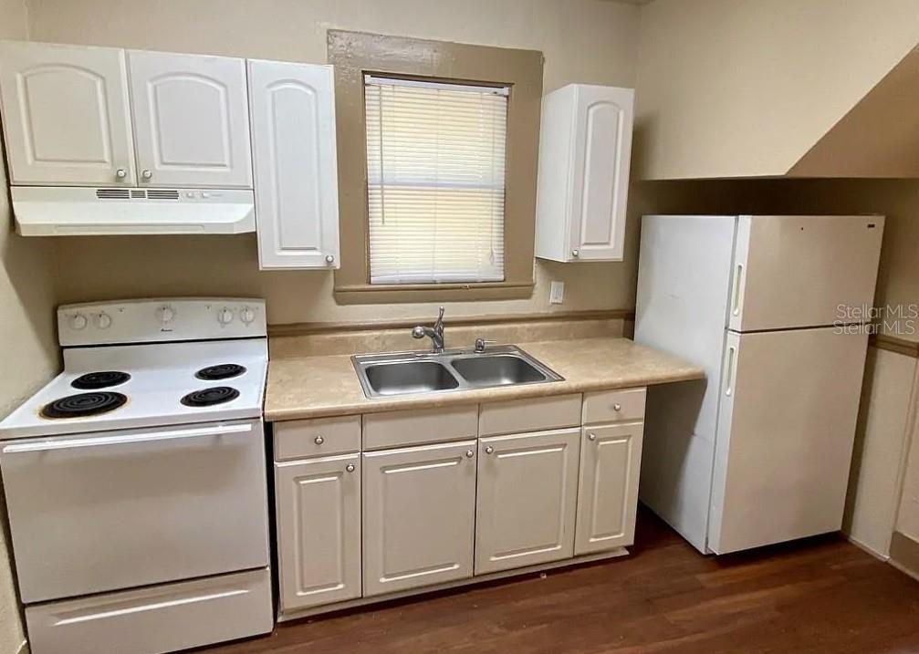 A kitchen features white cabinets, a white stove, a double sink, and a white refrigerator — 110 W 13TH STREET, SANFORD, FL