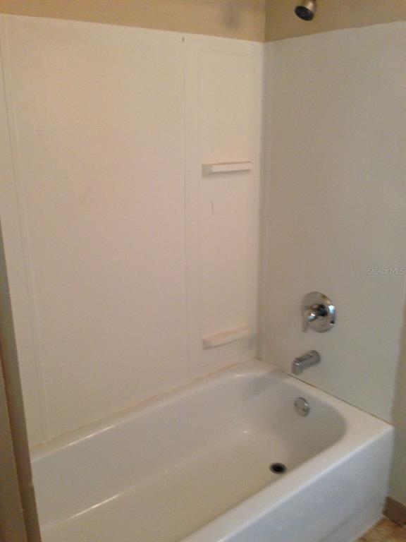 A white bathtub with a showerhead and wall surround in a bathroom — 110 W 13TH STREET, SANFORD, FL