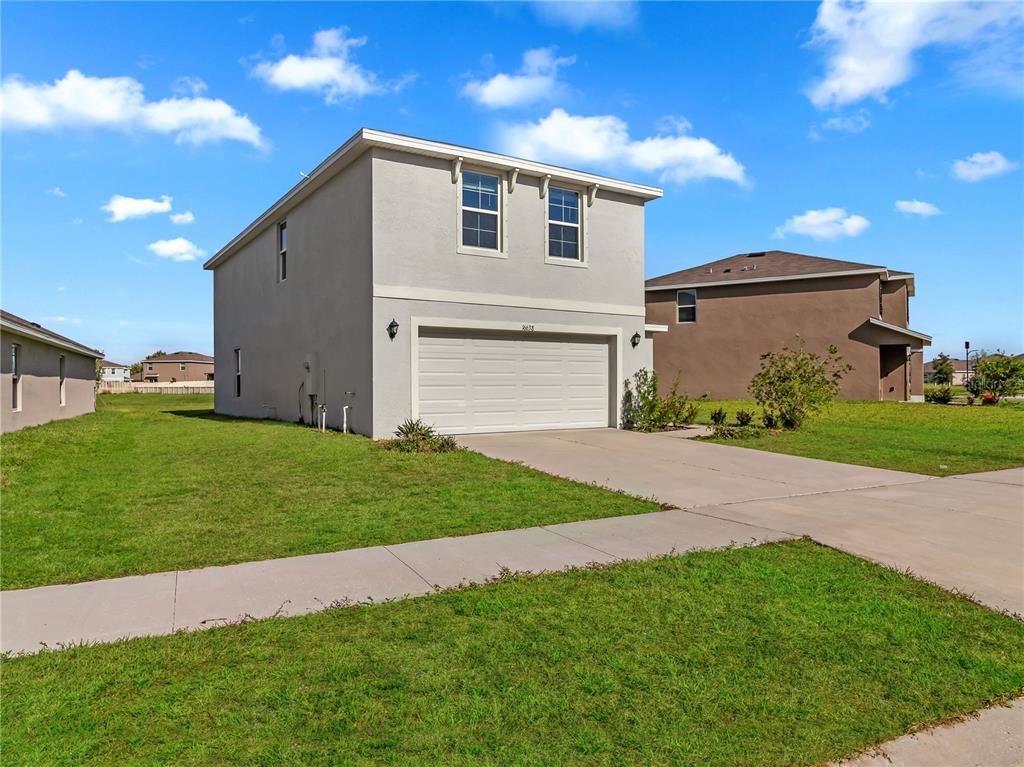 A two-story house with a light-colored stucco exterior and a two-car garage — 16638 MOSAIC OAR DRIVE, WIMAUMA, FL