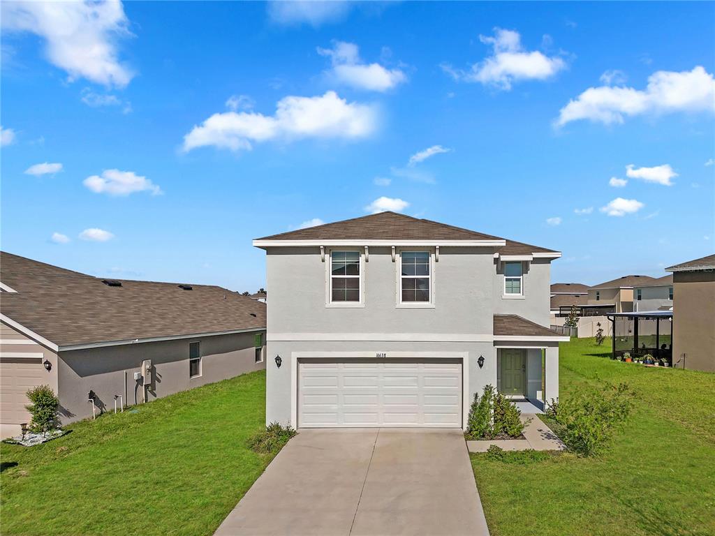 A two-story suburban house with a light gray stucco exterior and a two-car garage — 16638 MOSAIC OAR DRIVE, WIMAUMA, FL