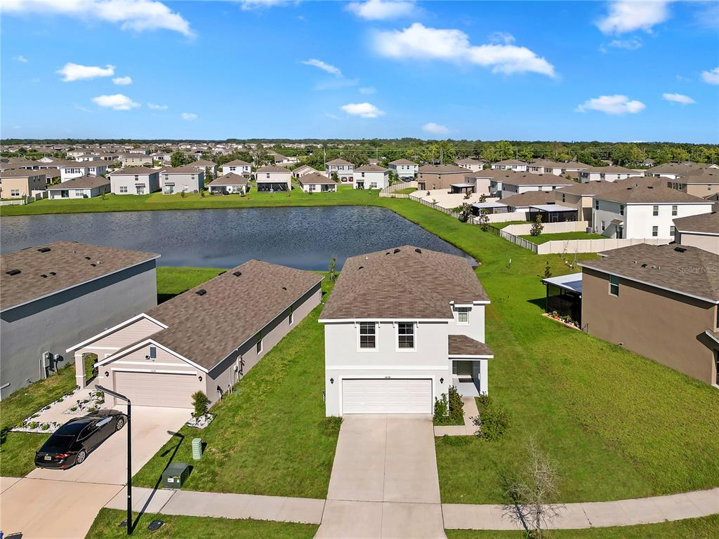 An aerial view shows a two-story suburban house with a garage and a nearby pond — 16638 MOSAIC OAR DRIVE, WIMAUMA, FL