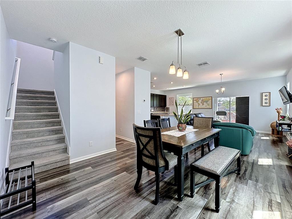 A dining area with a wooden table and bench sits beside a carpeted staircase — 246 ABERDEEN ST, DAVENPORT, FL