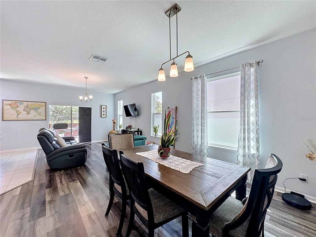 A dining area with a wooden table and chairs sits in an open-concept living space — 246 ABERDEEN ST, DAVENPORT, FL