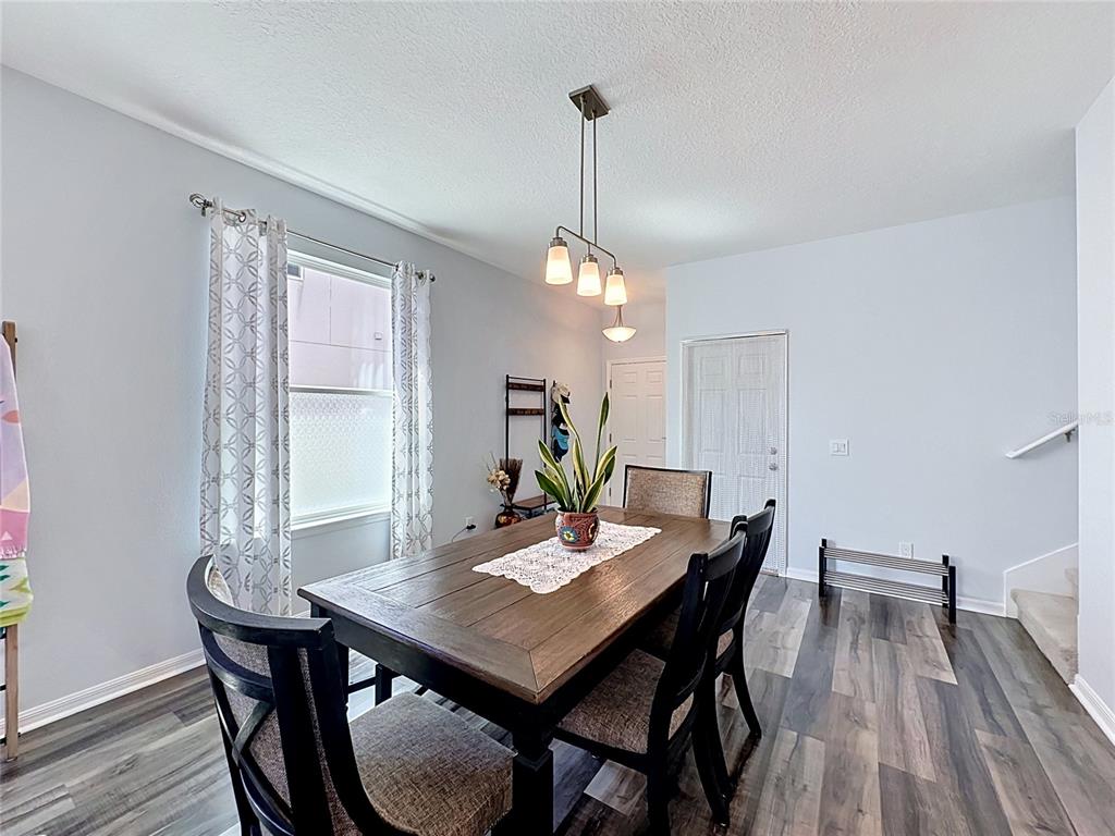 A dining room features a wooden table, black chairs, a pendant light, and wood-look flooring — 246 ABERDEEN ST, DAVENPORT, FL