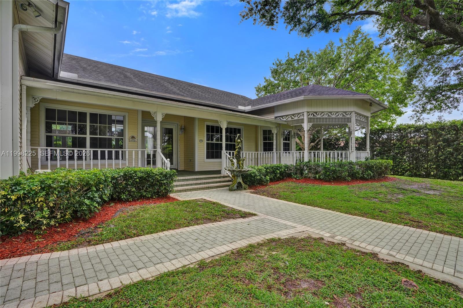 A yellow house features a covered porch, a gazebo, and a brick paver walkway — 12350 NW 6th St, Plantation FL 33325, PLANTATION, FL