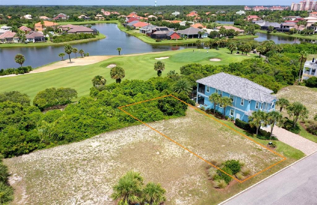 An aerial view shows a vacant residential lot next to a blue house near a golf course — 39 CINNAMON BEACH WAY, PALM COAST, FL