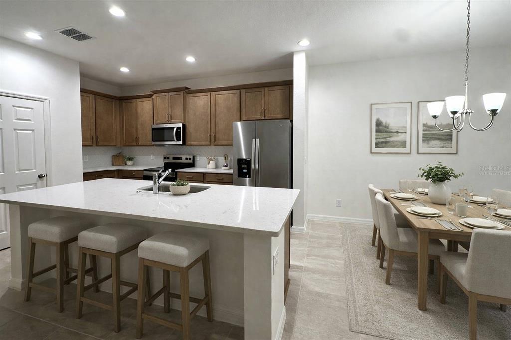 A kitchen with a white island, wooden cabinets, and an adjacent dining area with seating — 668 BIRDSWILL LANE, DELAND, FL