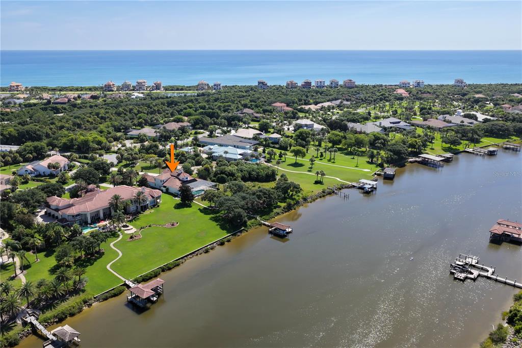 A boat dock with a covered slip sits on a canal in front of houses — 1 CAPRI COURT, PALM COAST, FL