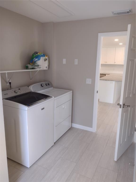 A laundry room with white appliances, a wall shelf, and light tile flooring — 830 E 18TH AVENUE, NEW SMYRNA BEACH, FL