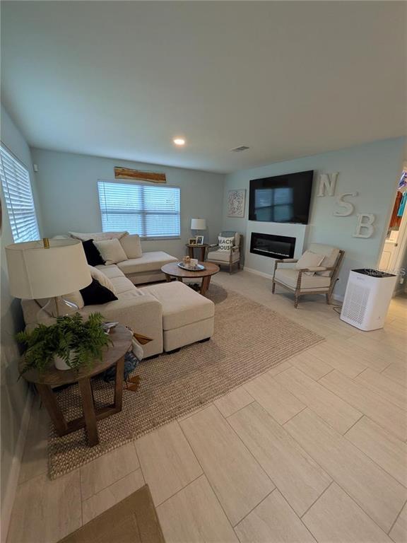 A living room features a sectional sofa, a fireplace, and light-colored tile flooring — 830 E 18TH AVENUE, NEW SMYRNA BEACH, FL