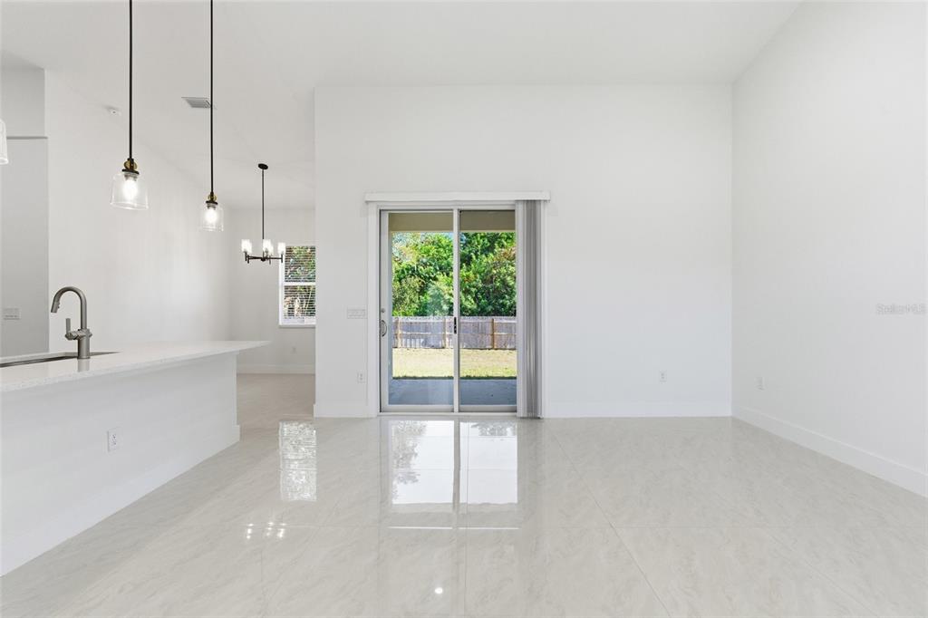 A bright, open-concept room features white walls, large floor tiles, and sliding glass patio doors — 1466 DEWITT STREET, PORT CHARLOTTE, FL