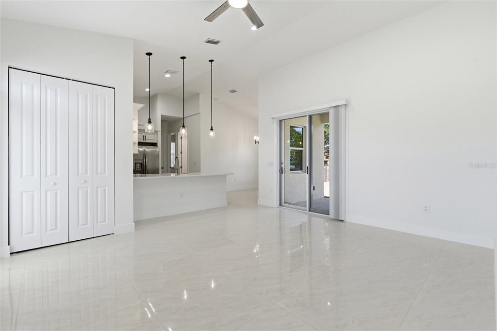 A bright, open-concept living area features white walls, glossy tile floors, and a kitchen island — 1466 DEWITT STREET, PORT CHARLOTTE, FL