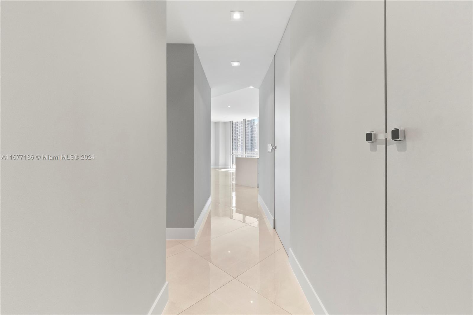 A hallway with light-colored tile flooring leads toward a bright room with floor-to-ceiling windows — 1010 SW 2nd Ave, Miami FL 33130, MIAMI, FL