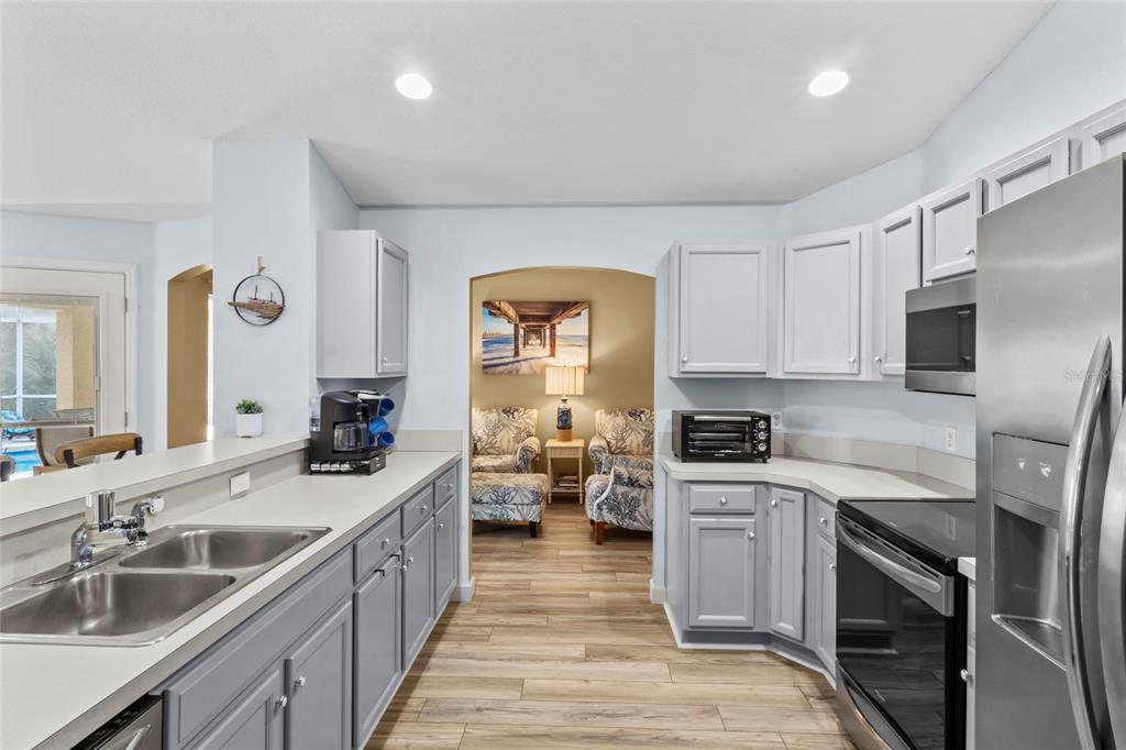 A kitchen with gray cabinets, stainless steel appliances, and a view into a sitting area — 136 OVERBROOK STREET, PORT CHARLOTTE, FL