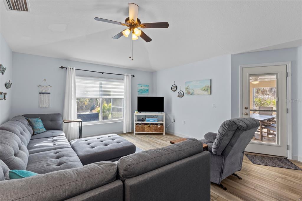 A living room features a grey sectional sofa, a recliner, a television, and a glass door — 136 OVERBROOK STREET, PORT CHARLOTTE, FL